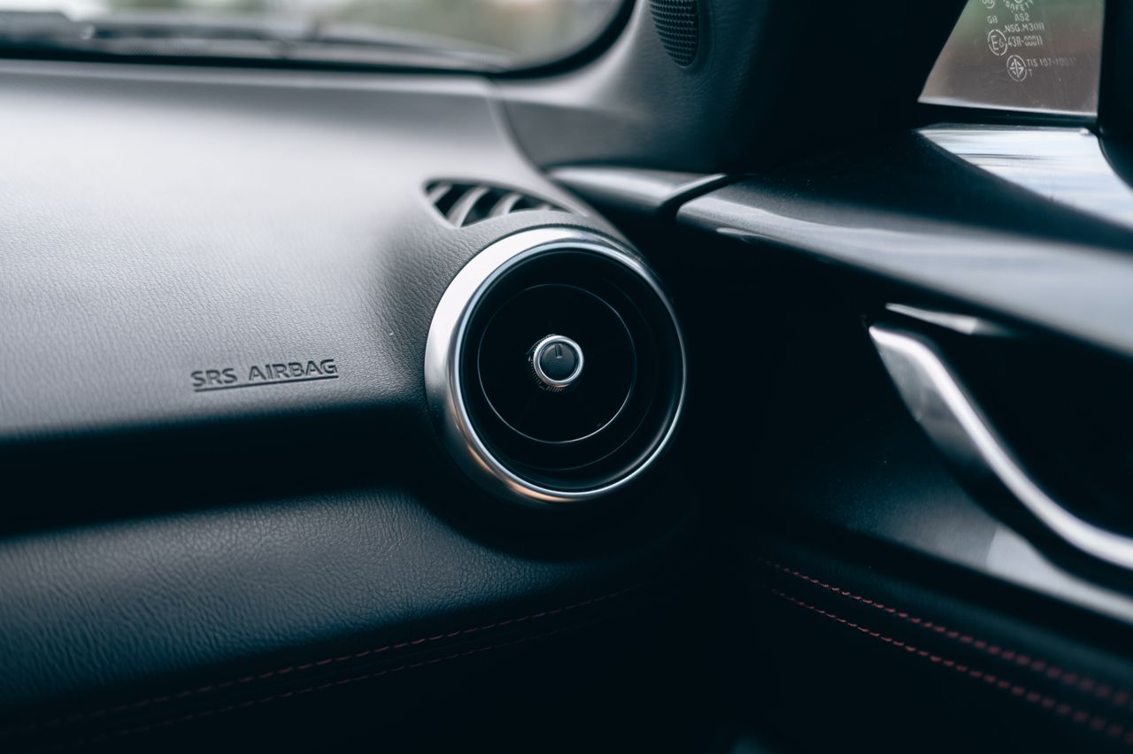 why-choose-me-02 Close-up of a car interior featuring an air vent and SRS airbag text on the dashboard.