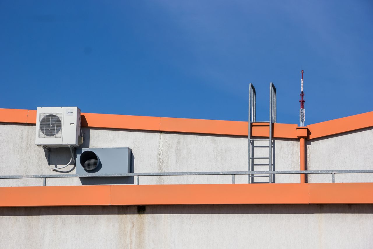 about-img-01 Rooftop view with HVAC unit, ladder, and clear sky background.