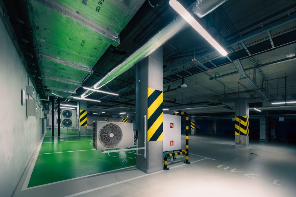 pexels photo 31462219 Sleek underground parking area with air conditioning units and green lighting.