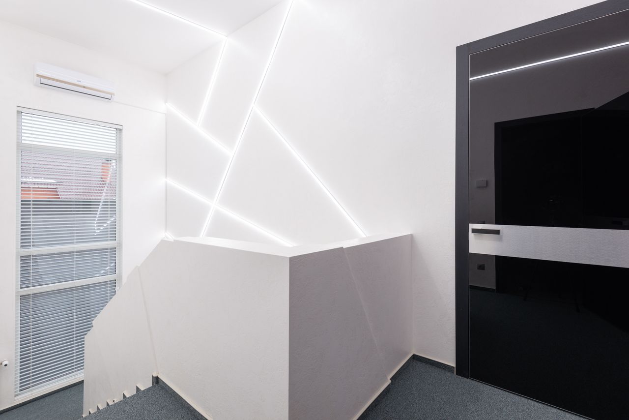 gallery-03 Door and staircase against jalousie and geometric lamps on white wall with air conditioning in building